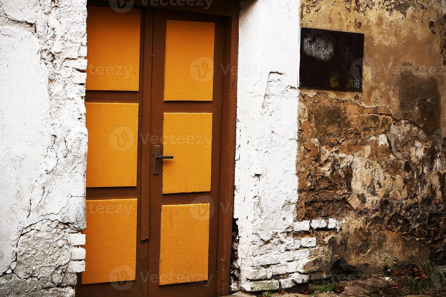 Yellow wooden entrance door with handle in white painted brick wall photo