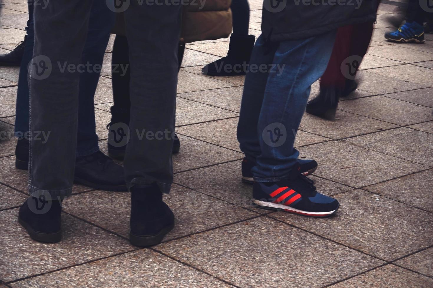 Las piernas de los hombres con calzado de pie sobre pavimento foto