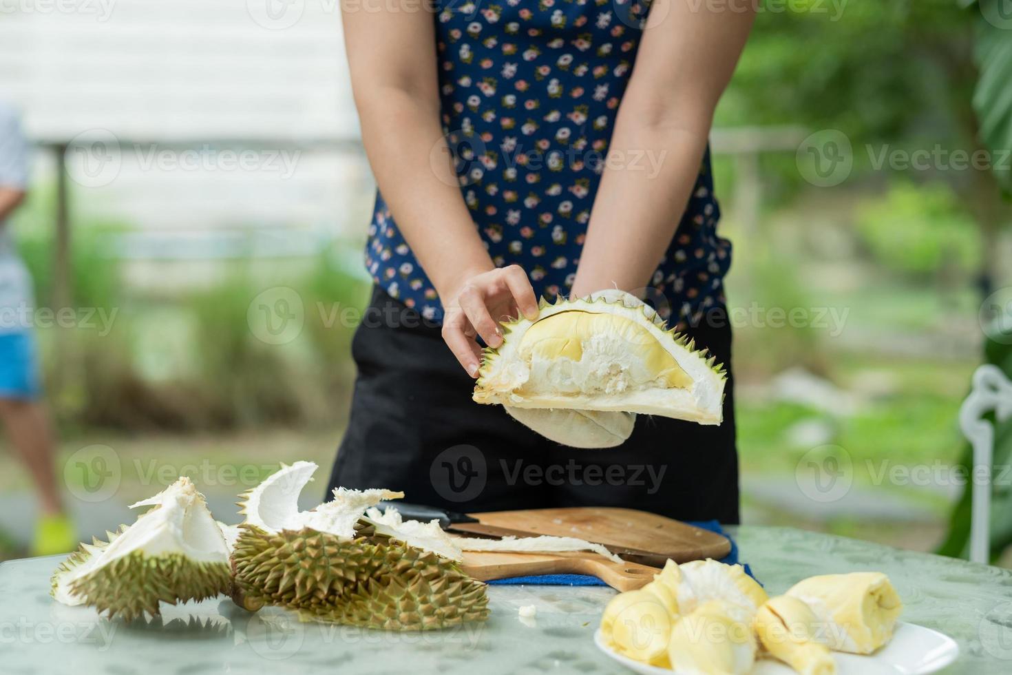 Primer plano mujer pelando la mano durian, rey de la fruta foto