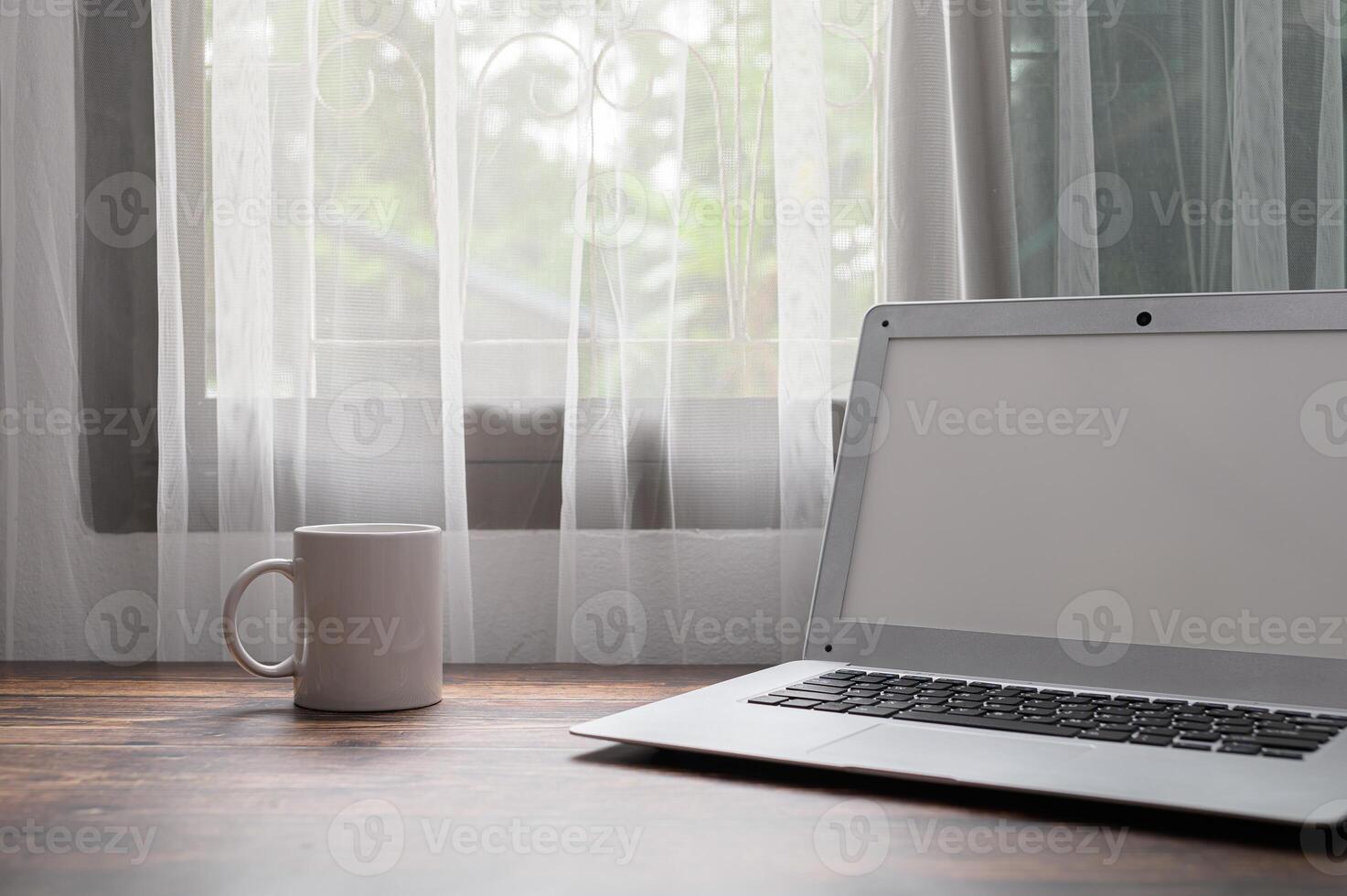 A laptop sitting on a table next to a coffee mug photo