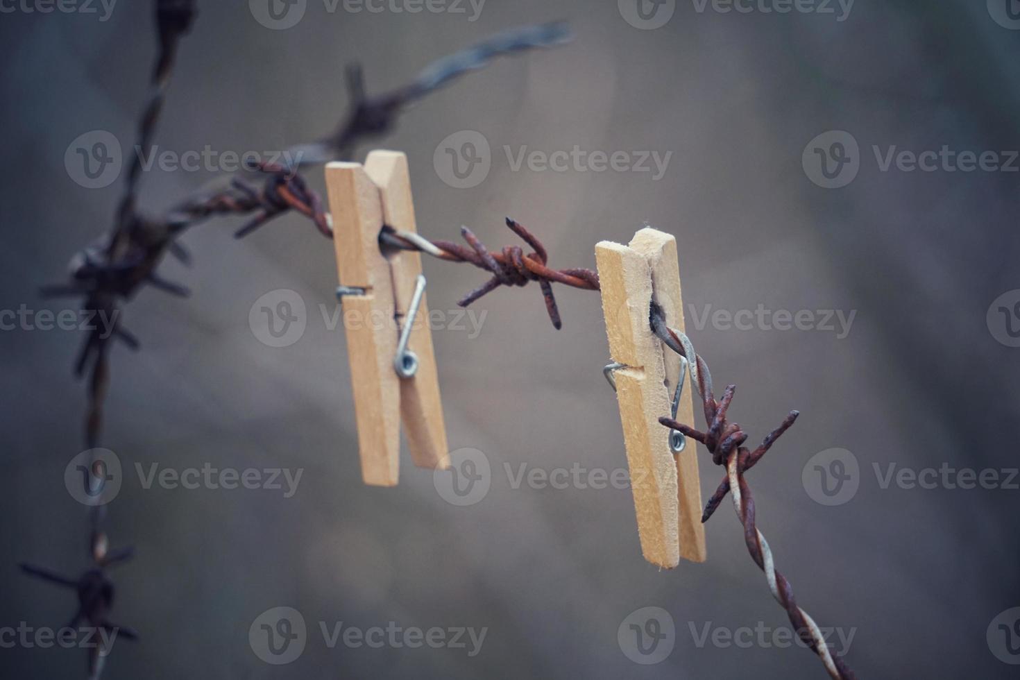 Wooden clothespin on the barbed wire fence photo