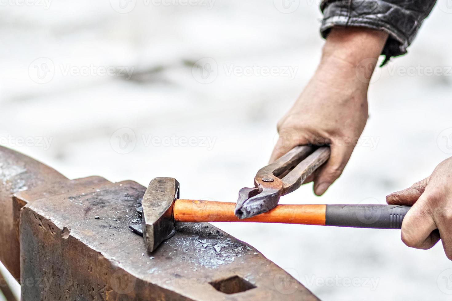 A blacksmith man forges a horseshoe on an anvil photo