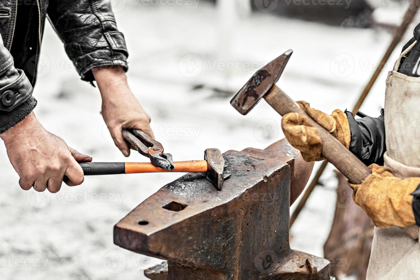 A blacksmith man and his son forge a horseshoe on an anvil photo