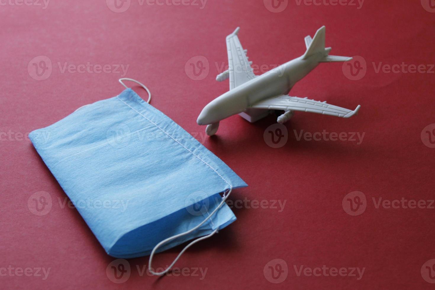 disposable mask and figure of an airplane on the red surface photo