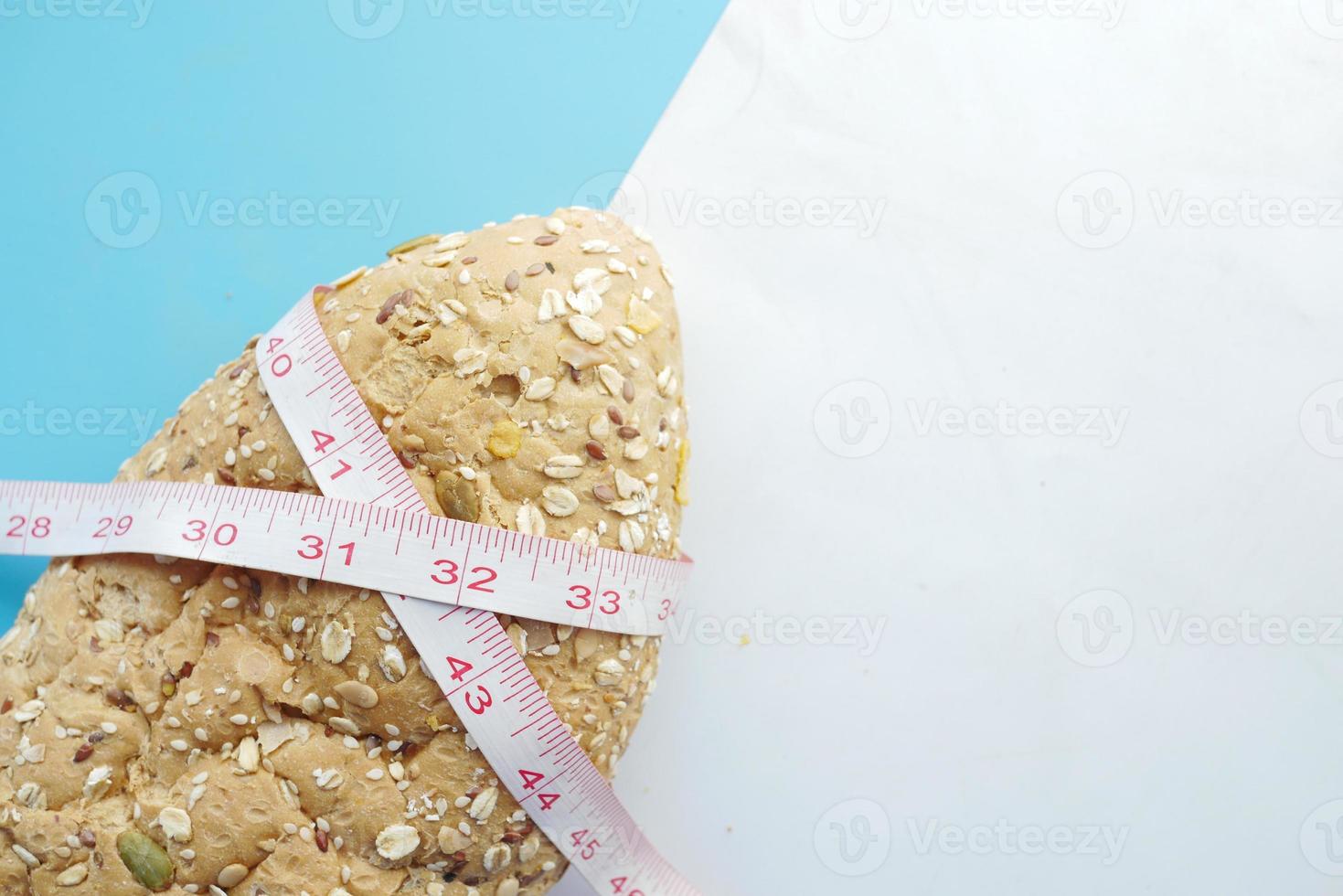Slice of whole meal bread and measurement tape on table photo