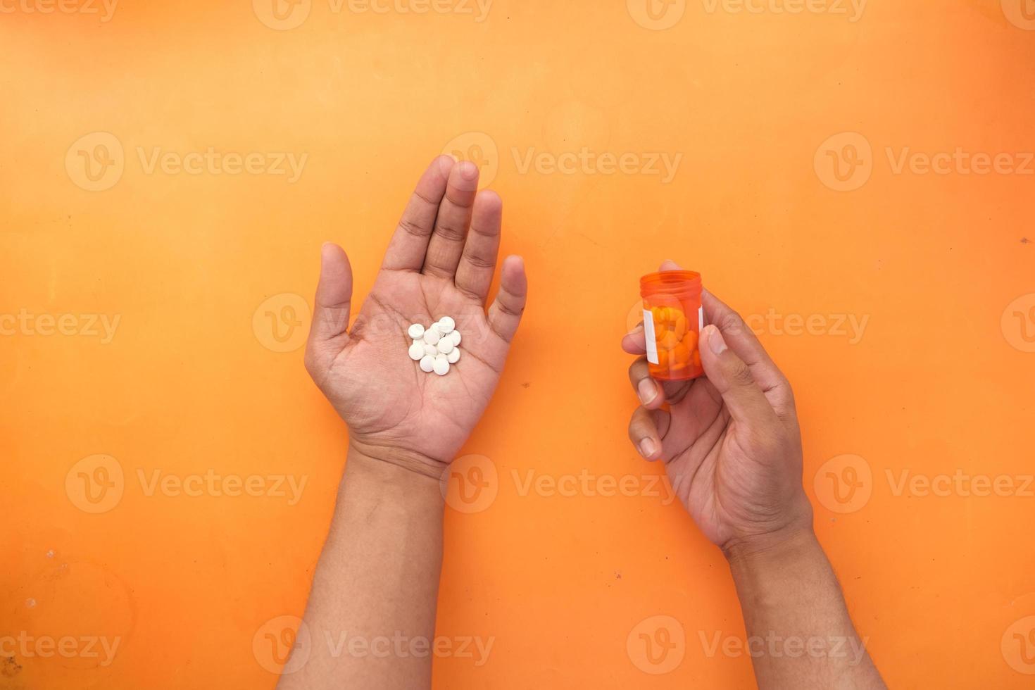 La mano del hombre con la medicina derramada fuera del contenedor de pastillas foto