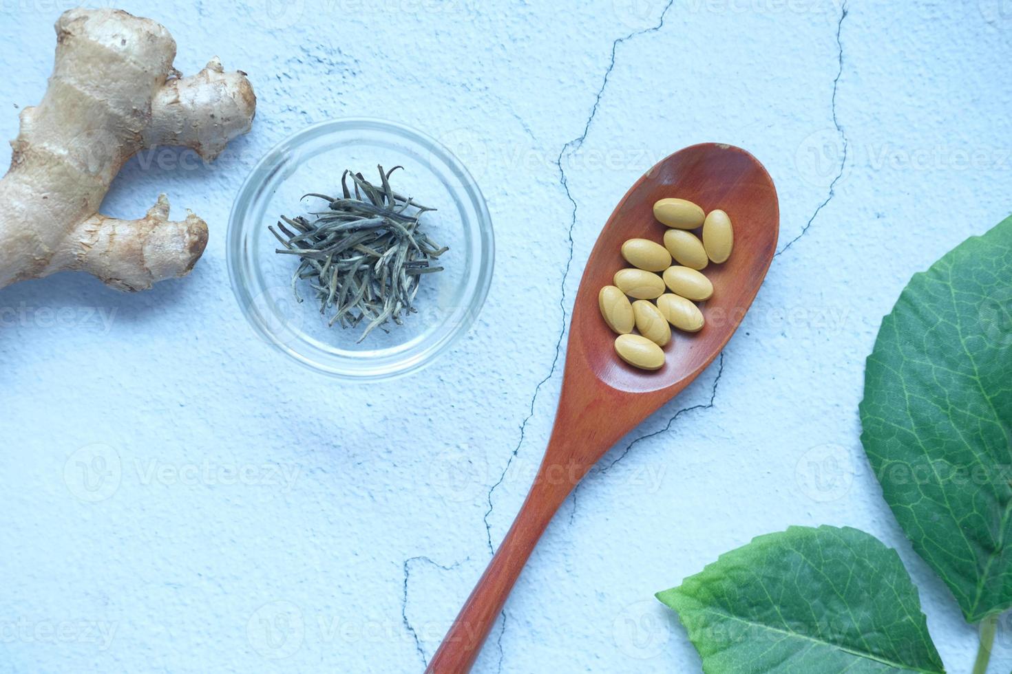 Herbal medicine on spoon and herbs on table photo