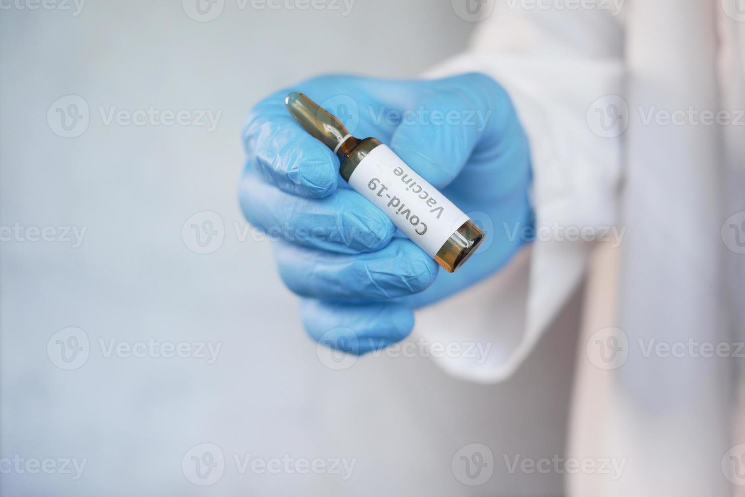 Mano en guantes de látex con ampolla de vidrio de vacuna con espacio de copia foto