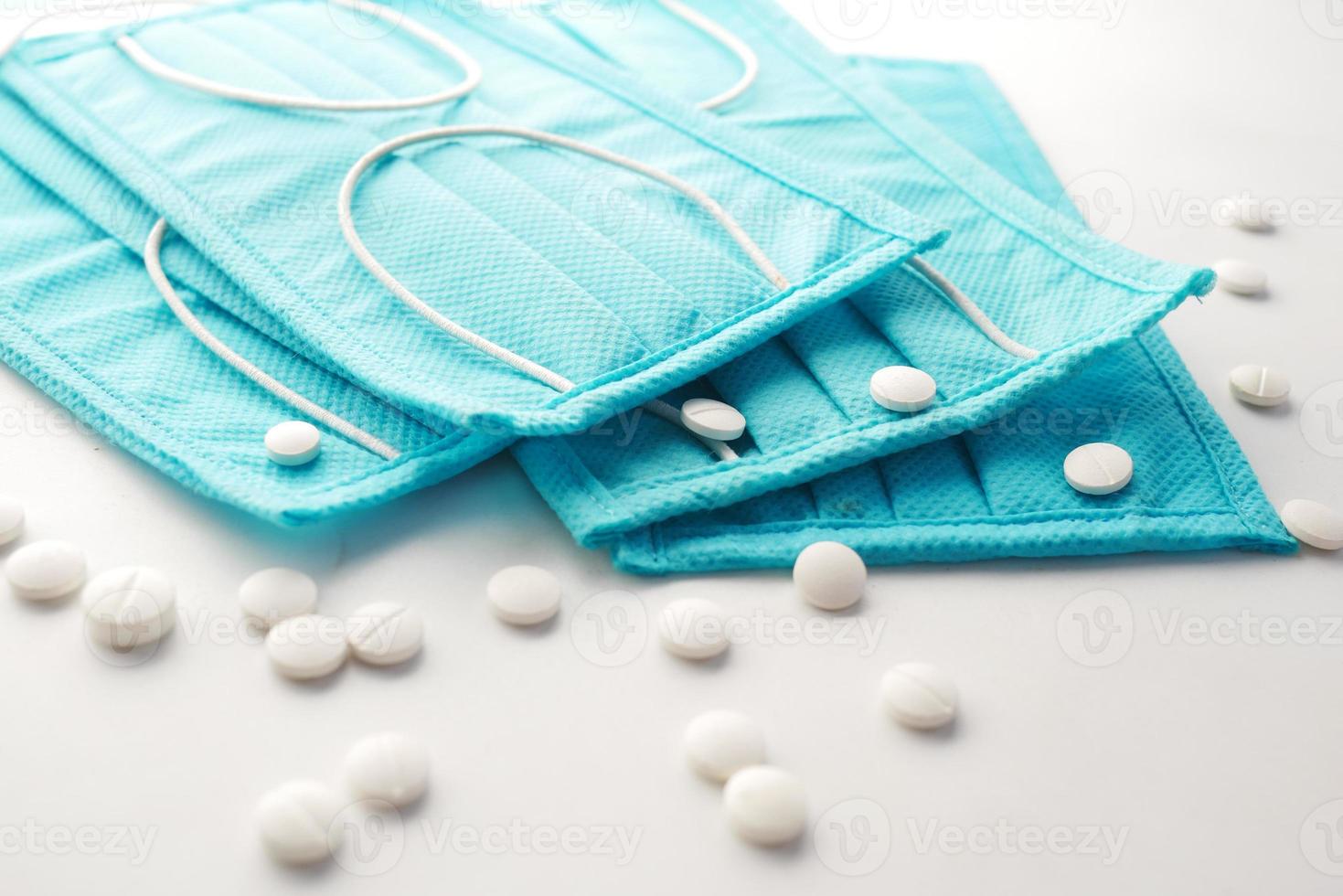 Close up of green surgical masks and medical pills on white background photo