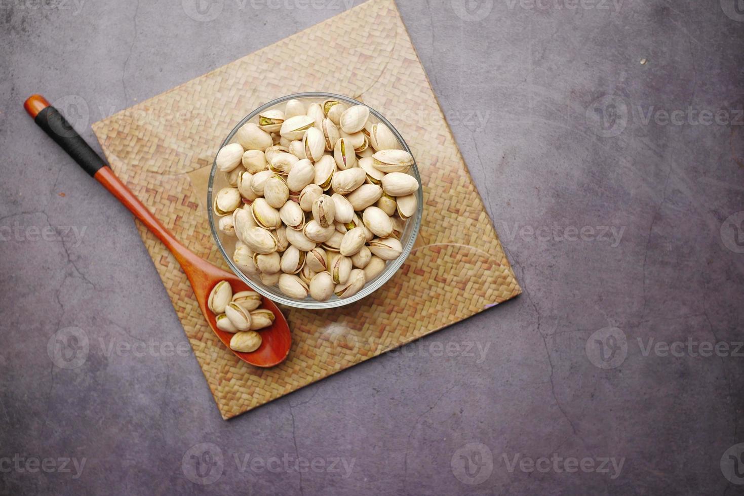 Pistachios nut in a bowl and wooden spoon on black background photo