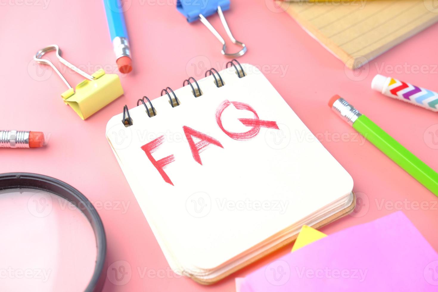 Hand drawing text FAQ on notepad on pink background photo