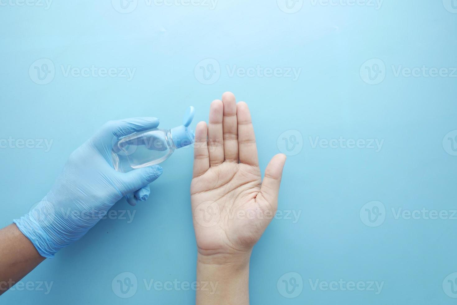 usando líquido desinfectante para prevenir el virus corona sobre fondo azul foto