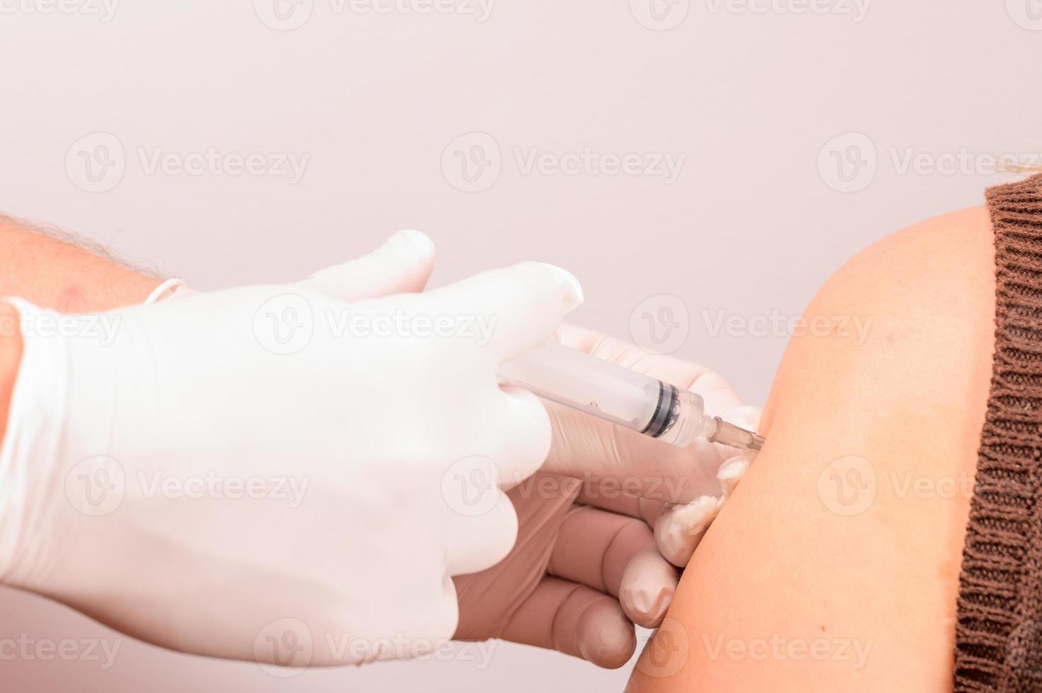 el ayudante de laboratorio inyecta un antiviral en la mano del paciente, realizando el procedimiento de cerca. foto