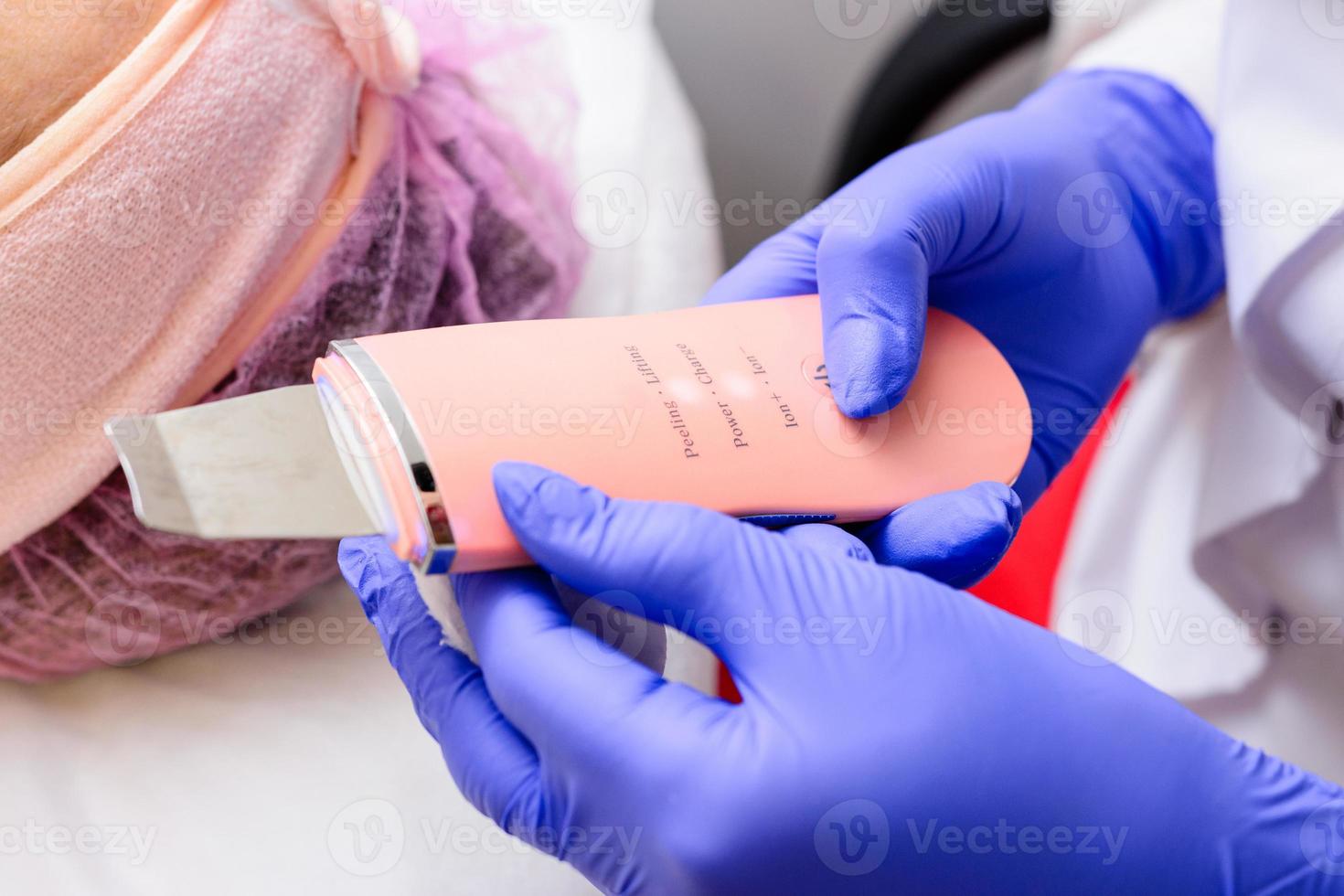 Facial cleansing with an ultrasonic scrubber. Cleansing the face from keratinized epithelium, excess fat, blockages of the sebaceous glands, comedones. photo