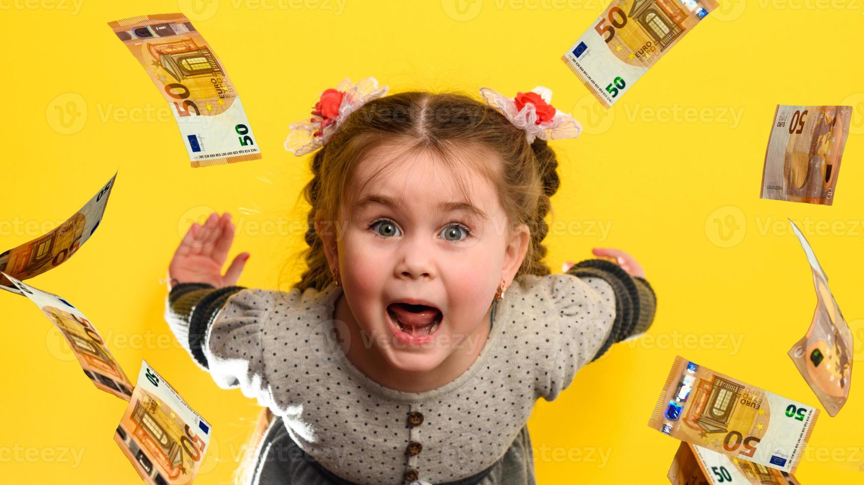 Little girl on a yellow background in the rain with money, euros flying
