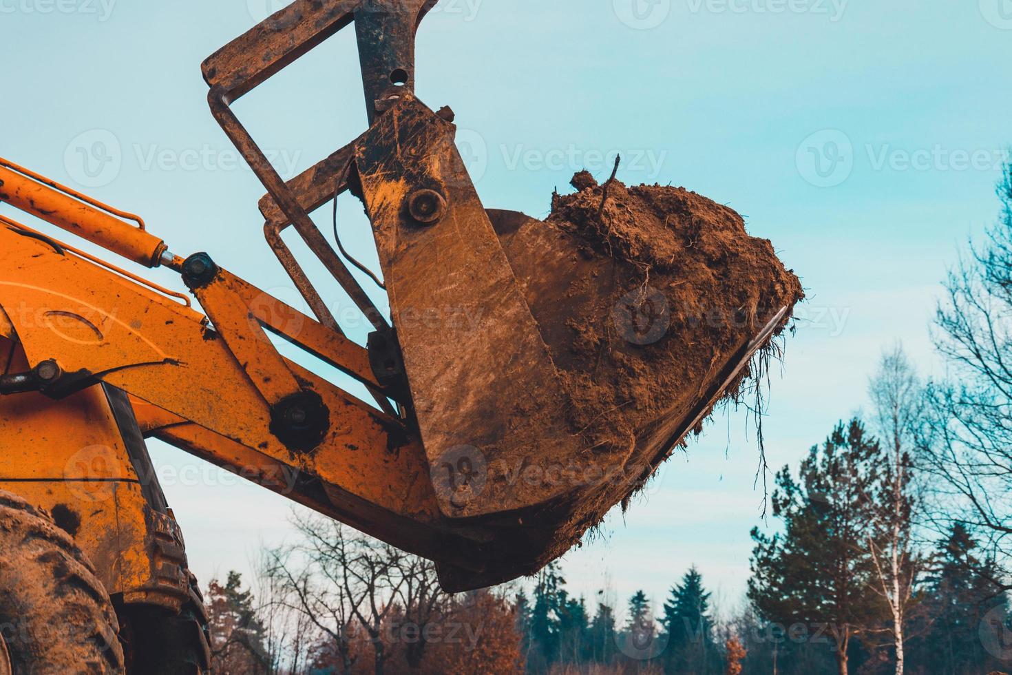 Closeup of a large bucket excavator digging the ground to set the road. photo