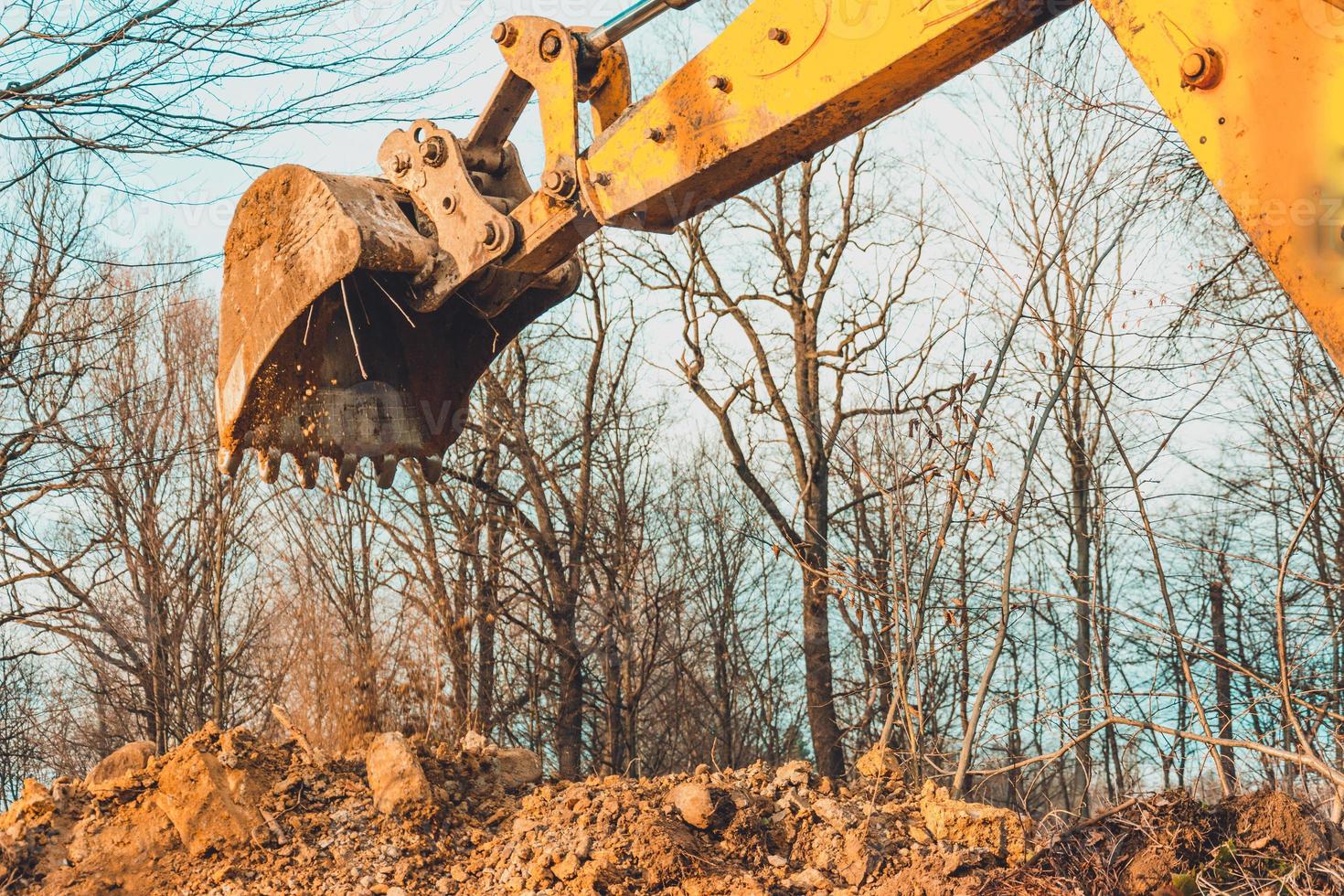 The excavator performs excavation work by digging the ground with a bucket in the forest. photo