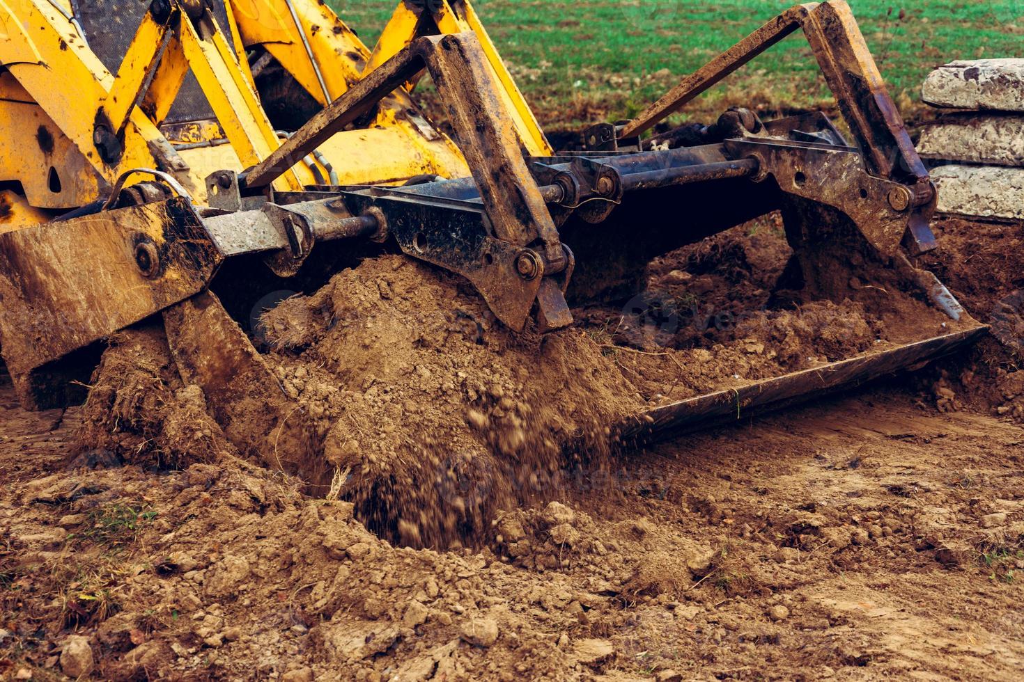 A close-up excavator loads soil into the bucket for further road installation. photo