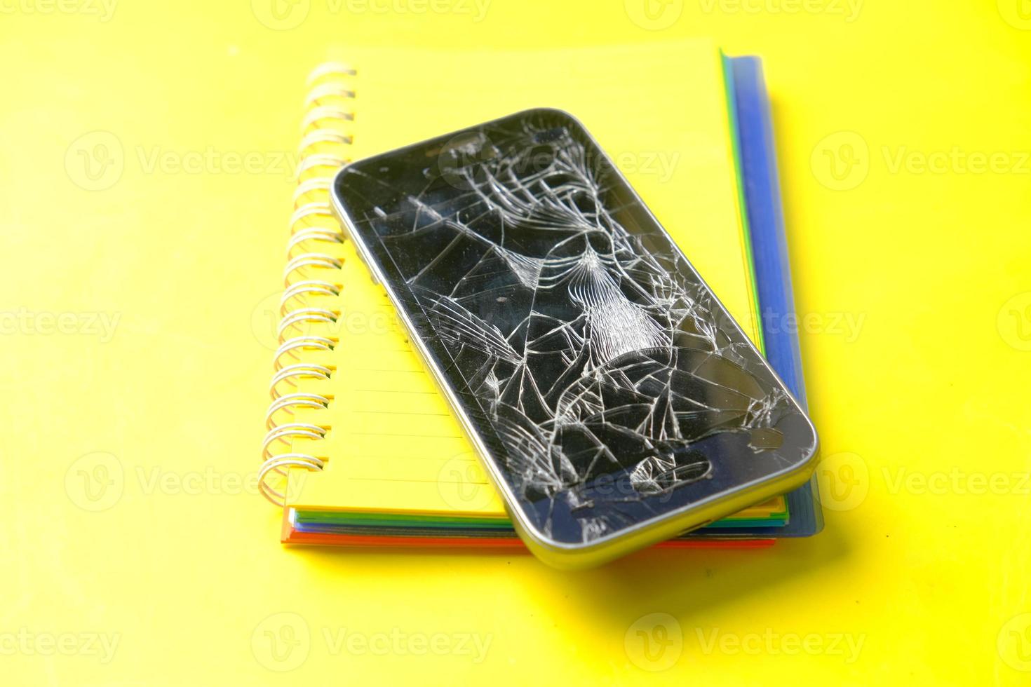 Top view of broken smart phone on yellow background photo