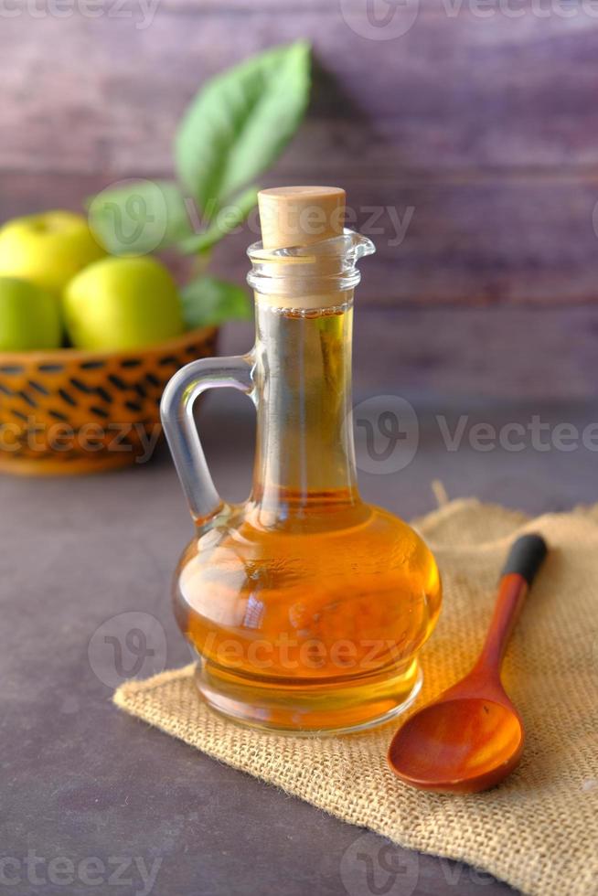 Apple vinegar in glass bottle with fresh green apple on table photo