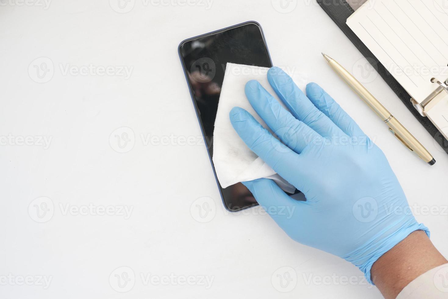 limpieza de la pantalla del teléfono móvil para prevenir virus en la mesa foto