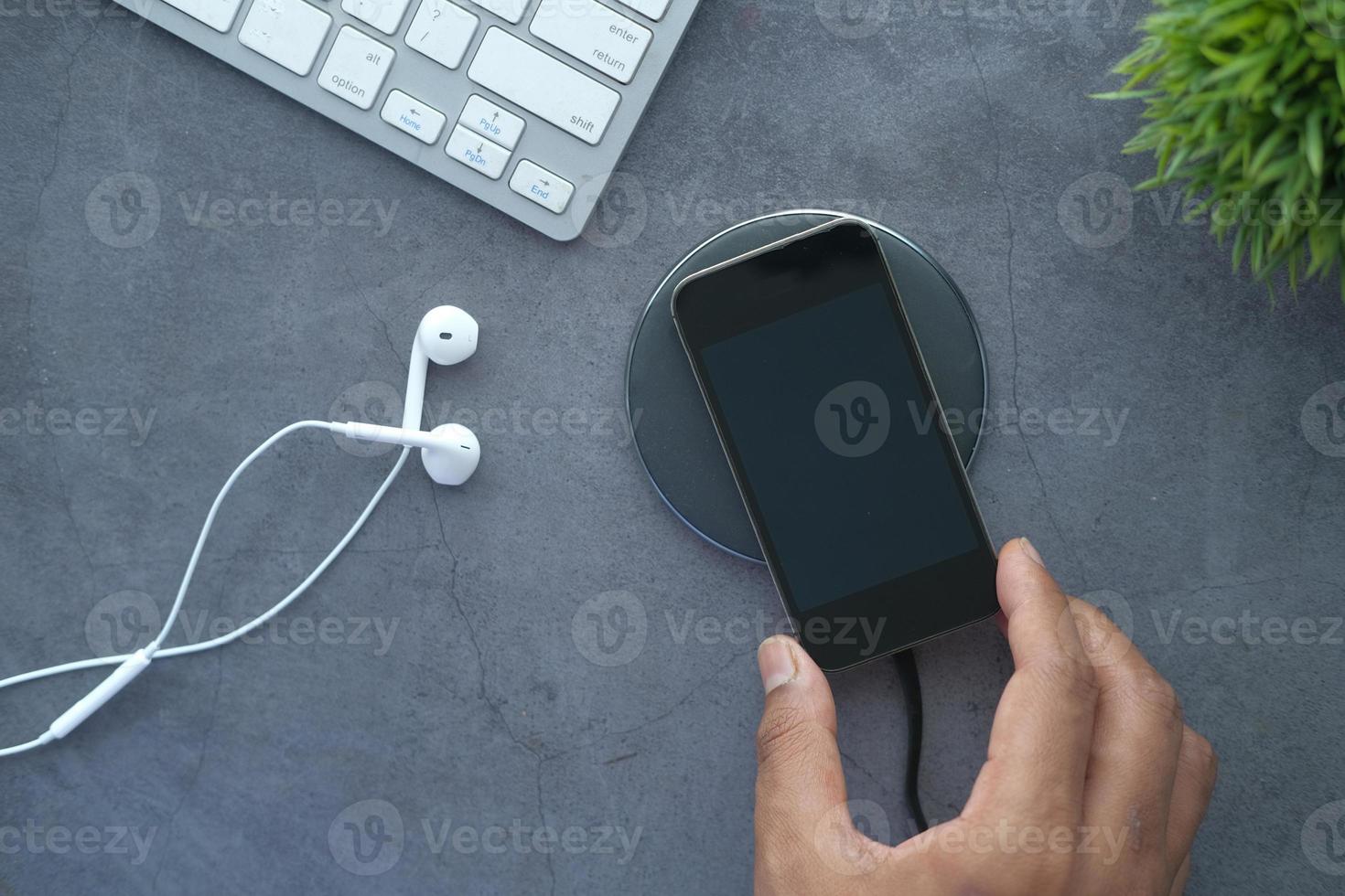 Man's hand charging smartphone using wireless charging pad, top view photo