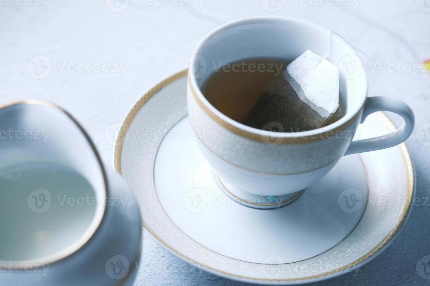 Green tea with tea bag on tiles background photo