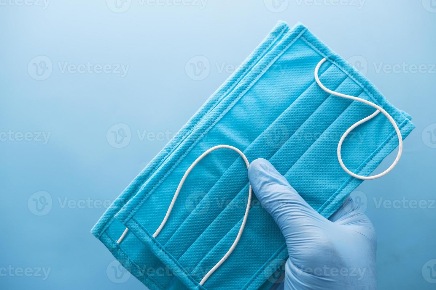 Hand in latex gloves holding surgical face mask, close up photo