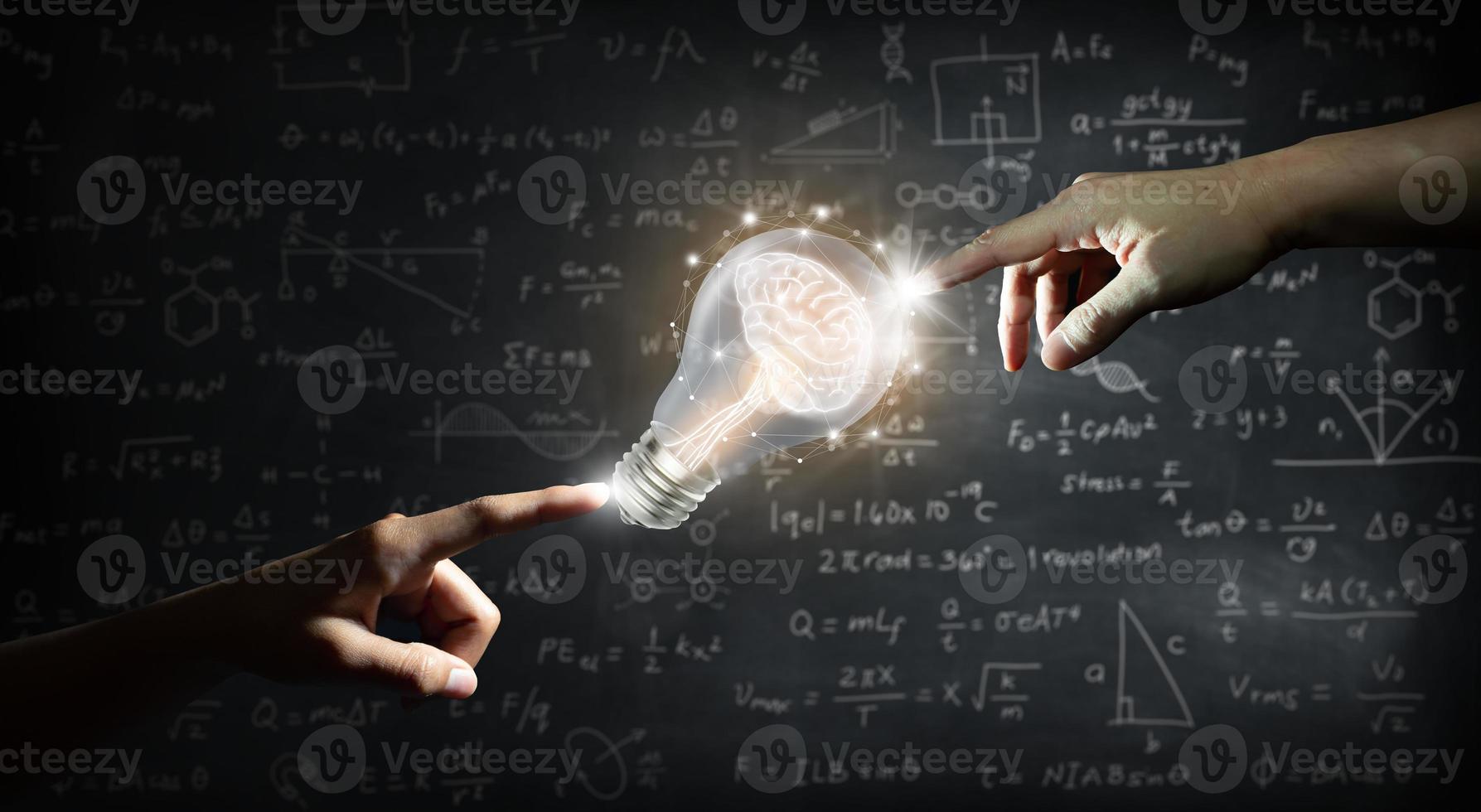 Hand pointing to a brain inside a light bulb on wall blackboard photo