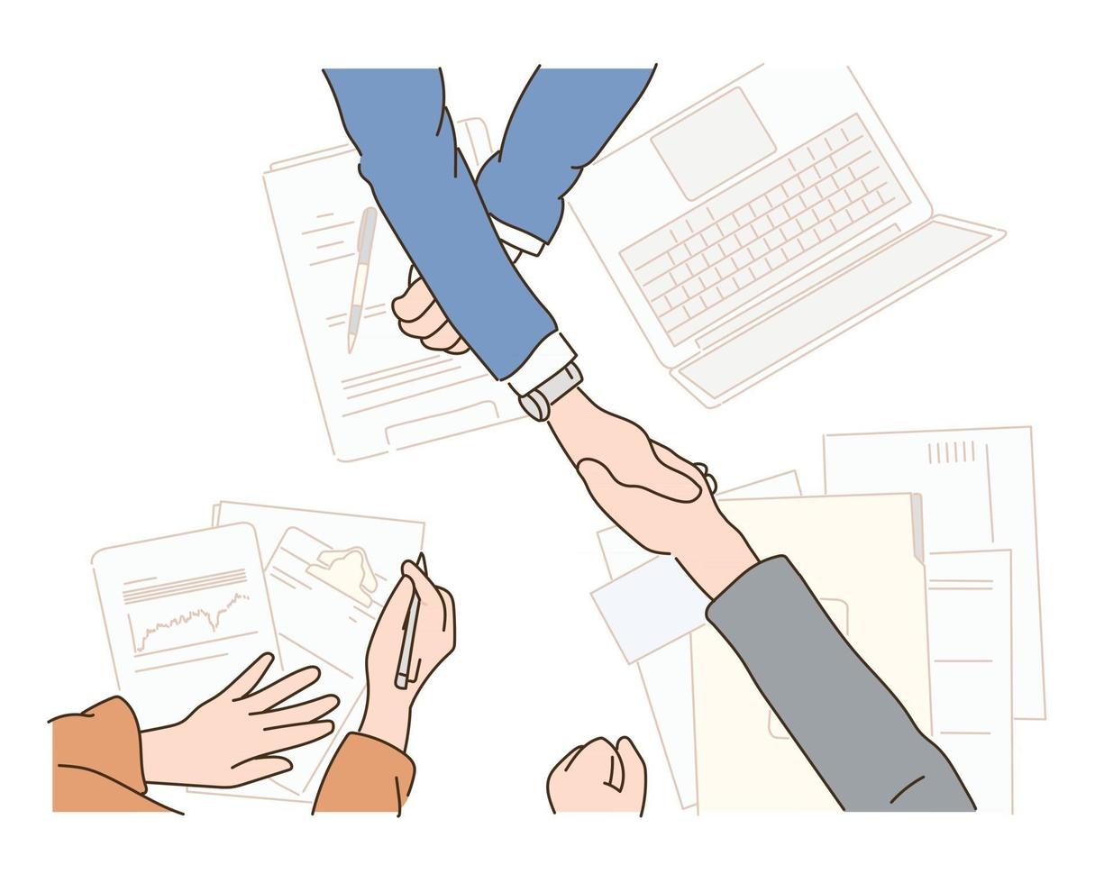 Hands shaking hands on a business table with piles of papers. vector