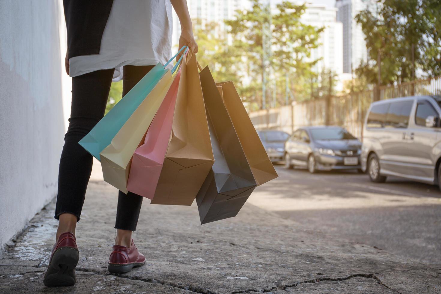Mano de mujer sosteniendo bolsas de compras después de ir de compras en el centro comercial y caminar al estacionamiento foto