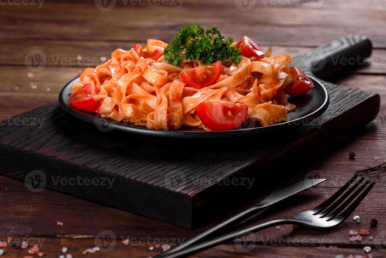 Deliciosa pasta fresca con salsa de tomate con especias y hierbas sobre un fondo oscuro foto