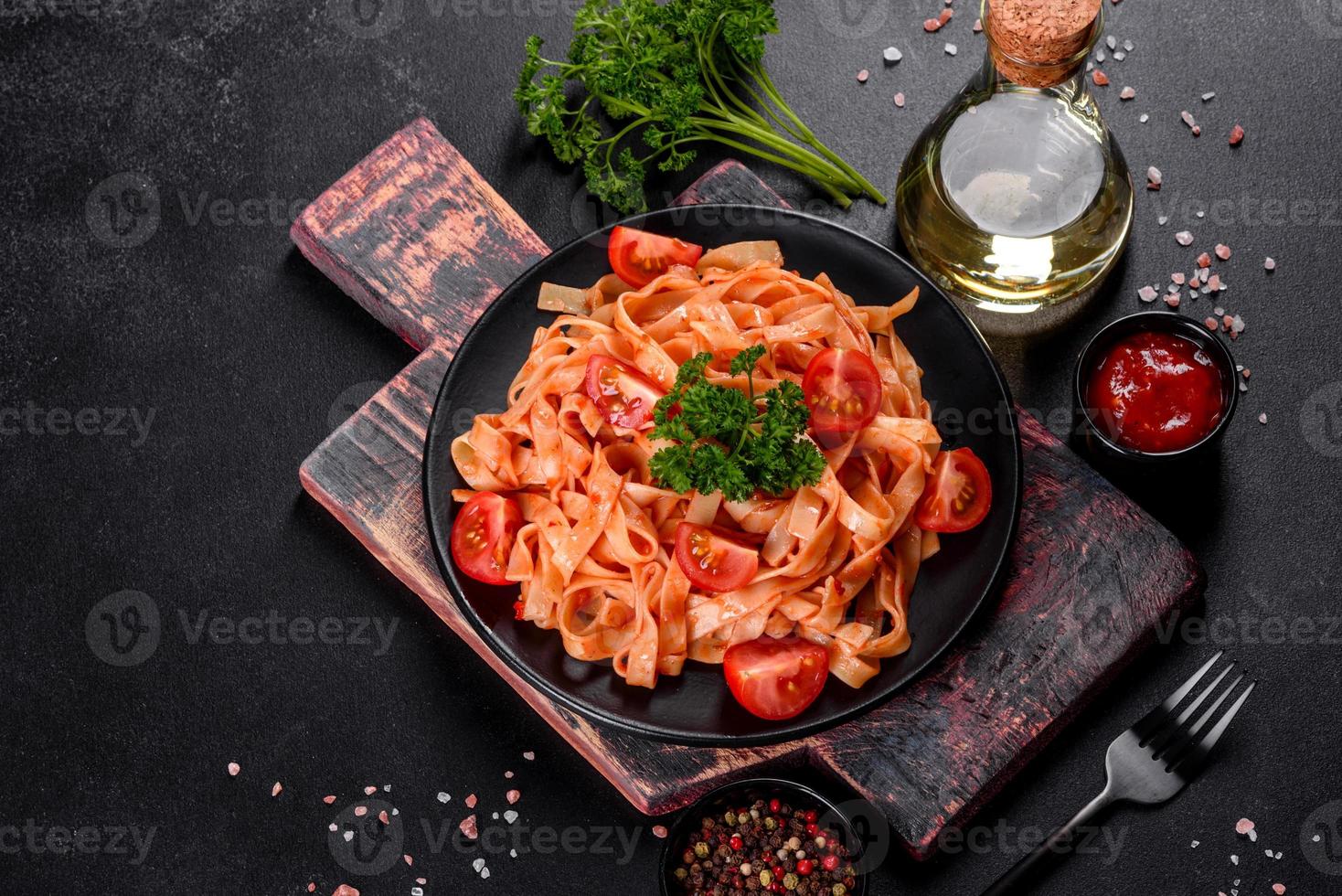 Delicious fresh paste with tomato sauce with spices and herbs on a dark background photo