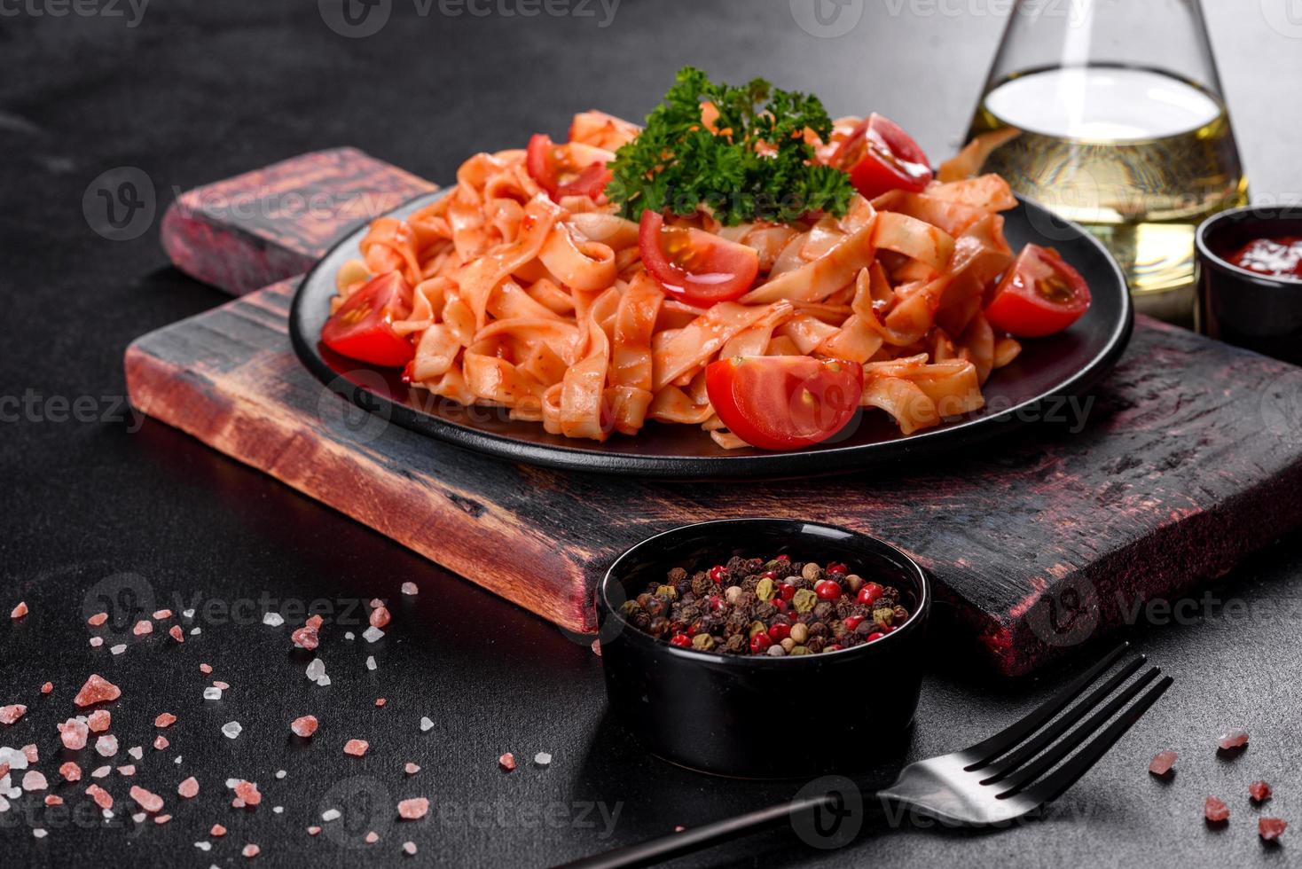 Delicious fresh paste with tomato sauce with spices and herbs on a dark background photo