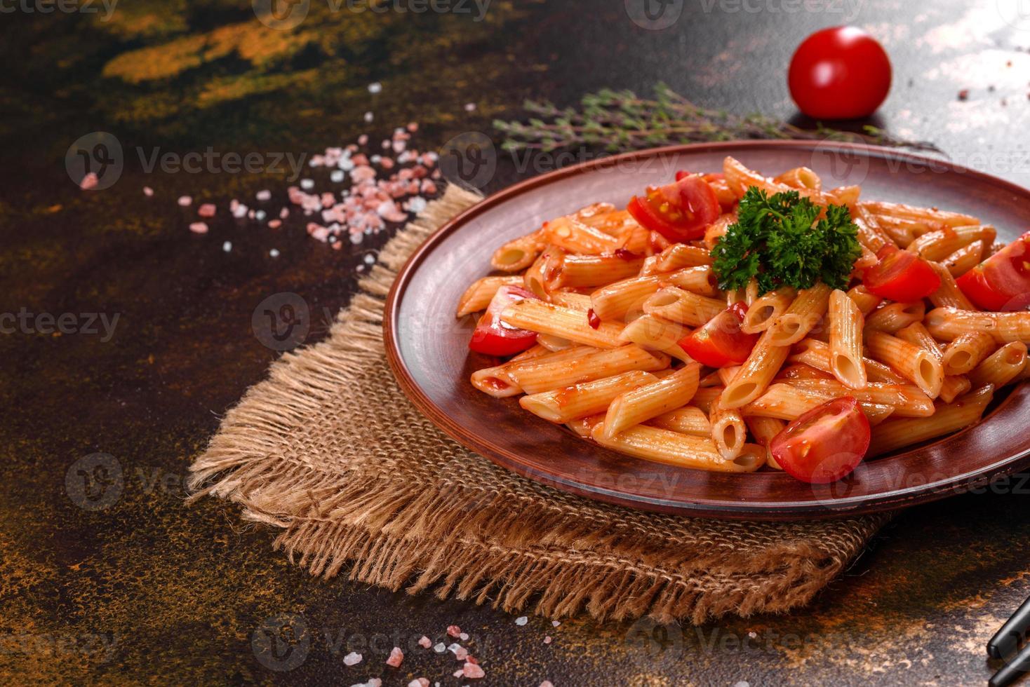 Deliciosa pasta fresca con salsa de tomate con especias y hierbas sobre un fondo oscuro foto