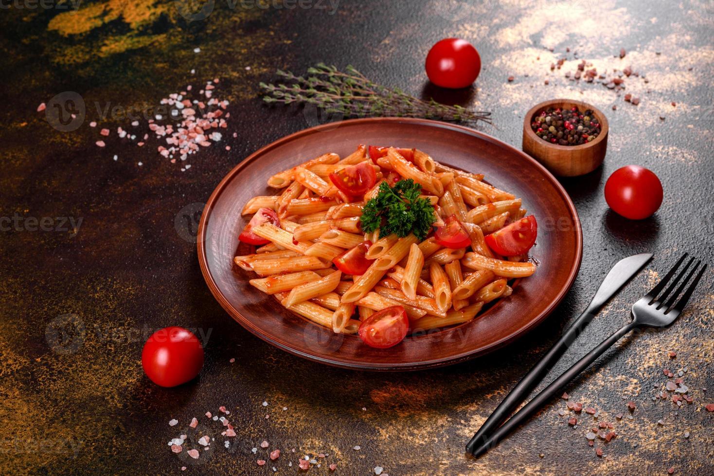 Delicious fresh paste with tomato sauce with spices and herbs on a dark background photo