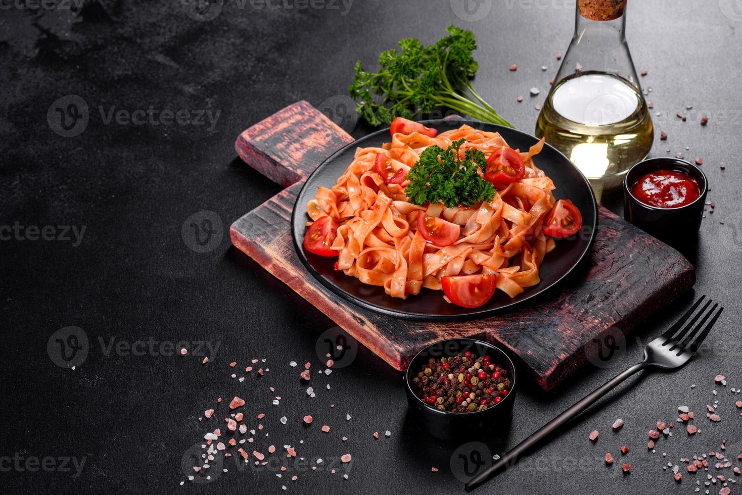 Delicious fresh paste with tomato sauce with spices and herbs on a dark background photo