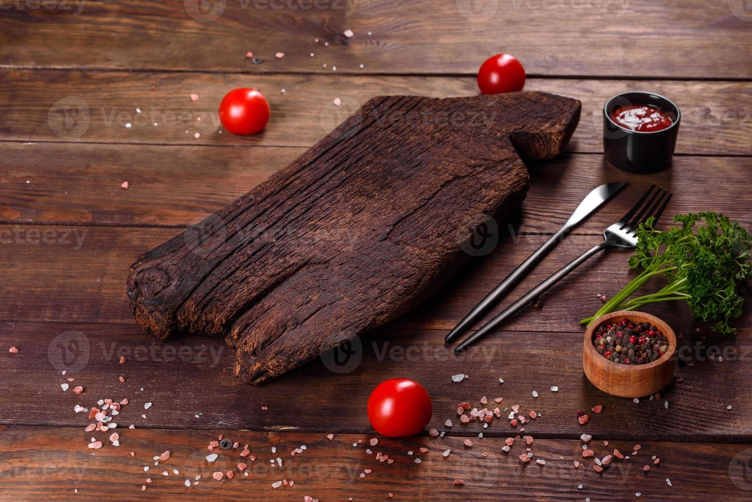 cortar tabla de madera, verduras y una mesa oscura especial foto