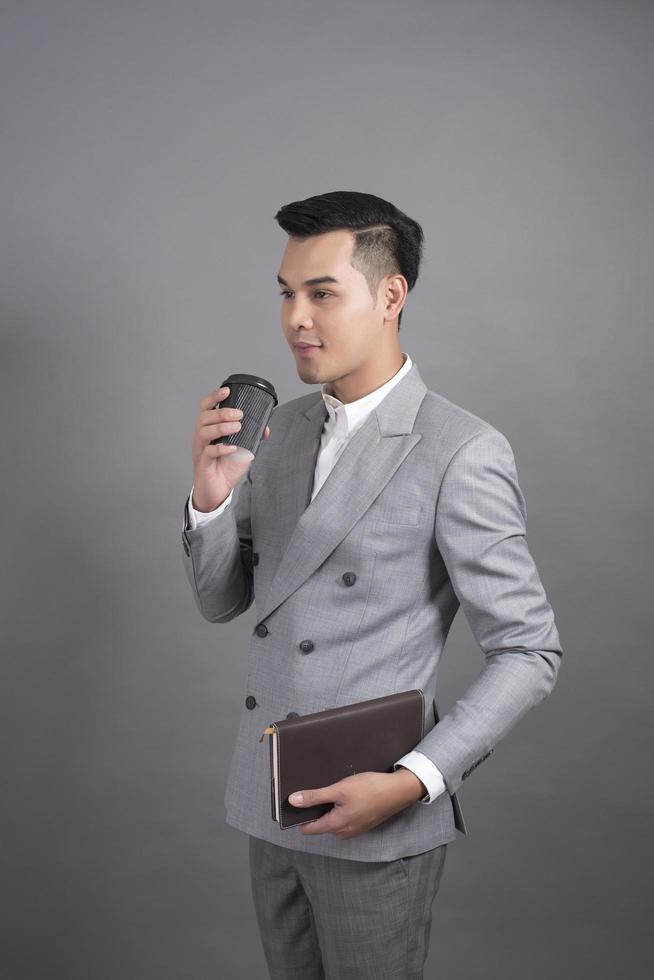 Businessman is drinking coffee break, portrait in studio grey background photo