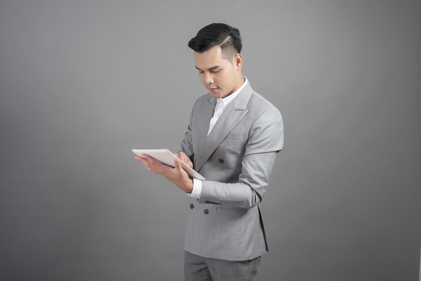 El empresario está usando tableta, retrato en fondo gris de estudio foto