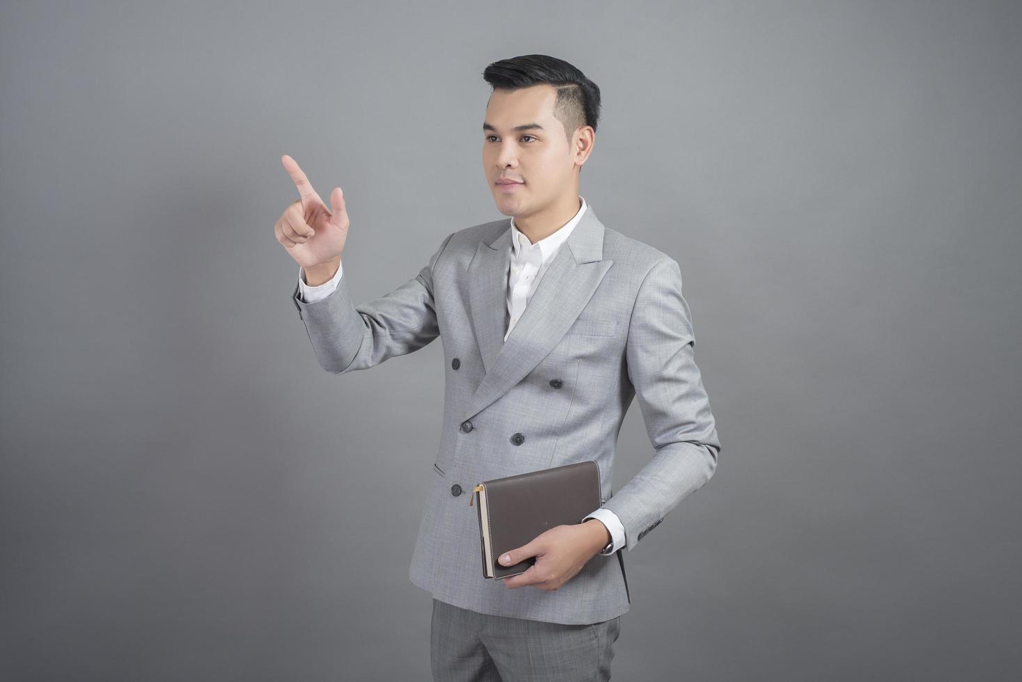 Businessman is touching virtual screen, portrait in studio grey background photo