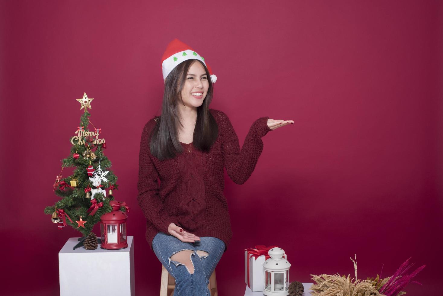 Beautiful Santa Claus girl in studio on red background, Christmas concept photo