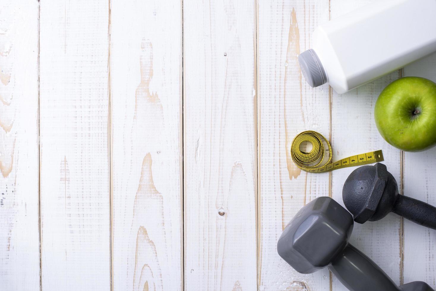 Equipos de fitness y comida sana sobre fondo blanco de madera foto