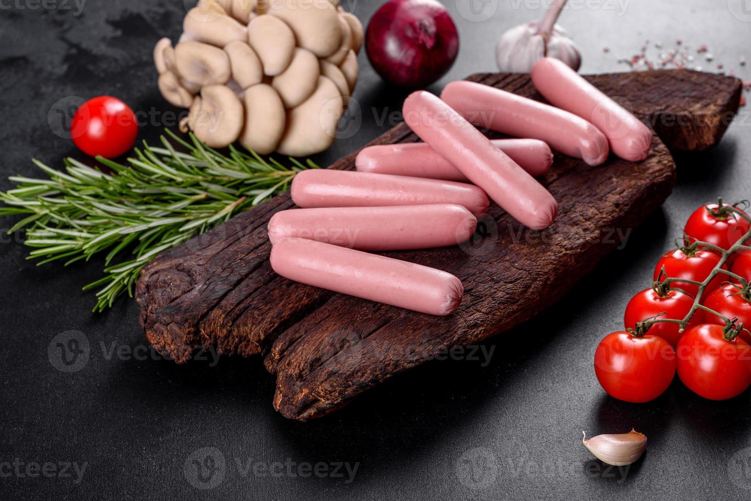 Boiled sausages on a wooden cutting board on a dark concrete background photo