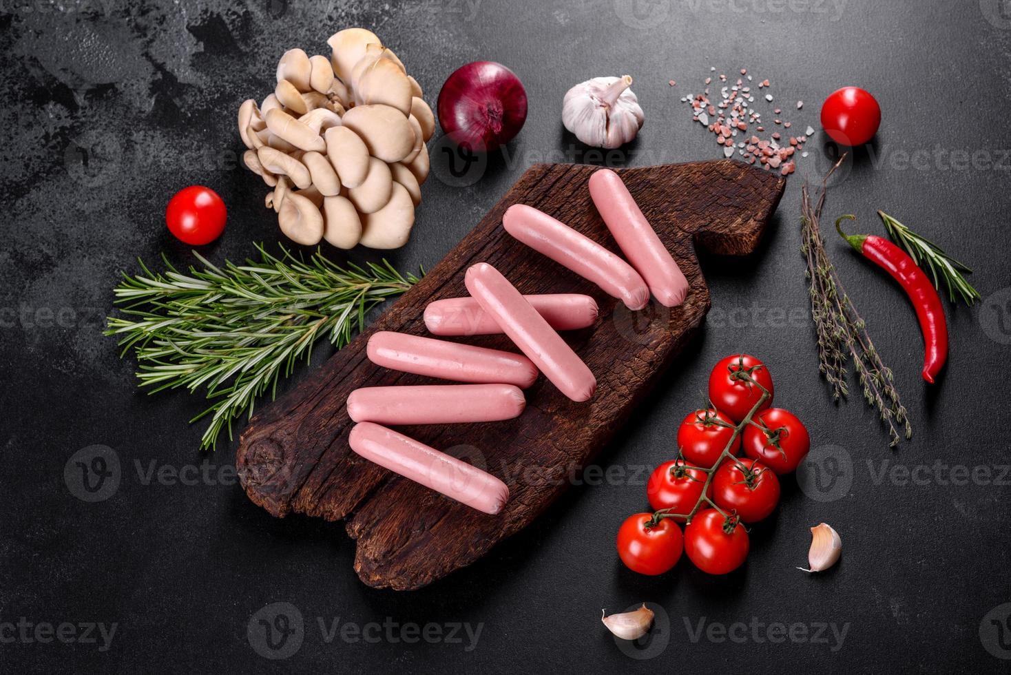 Boiled sausages on a wooden cutting board on a dark concrete background photo