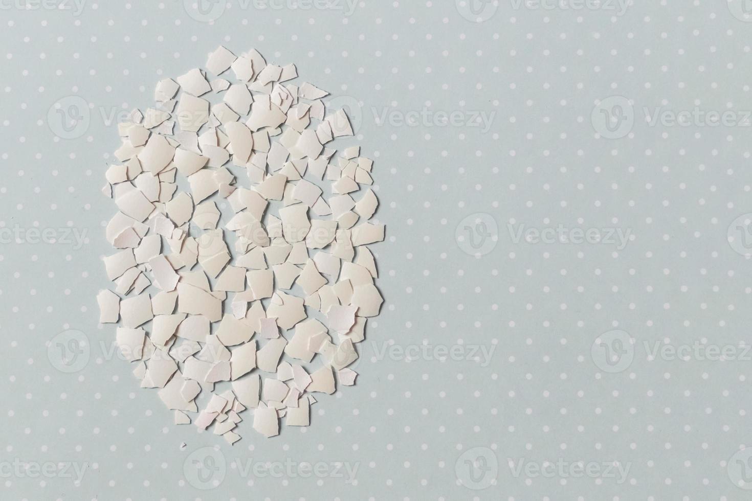 Pieces of white shell chicken egg, folded in the shape of an egg on a blue background photo