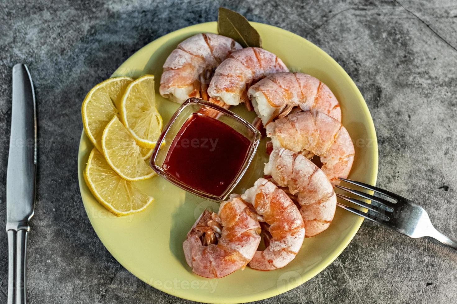 On a green platter, king prawns with lingonberry sauce, lemon and cutlery photo