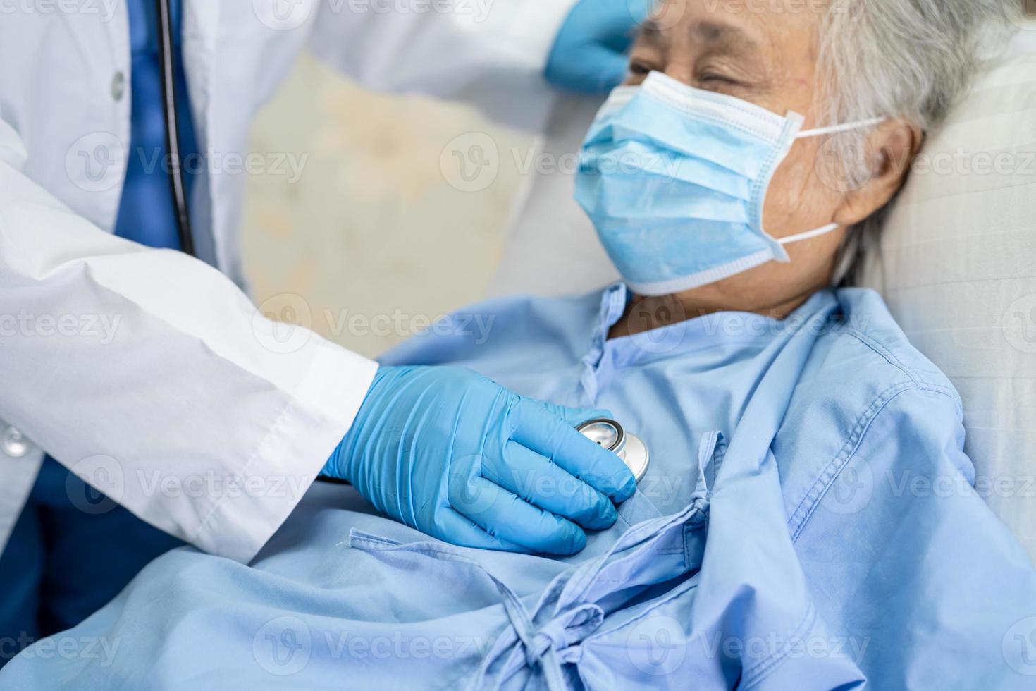 médico que usa estetoscopio para verificar que el paciente asiático mayor o anciano usa una mascarilla en el hospital para proteger la infección por el coronavirus covid-19. foto