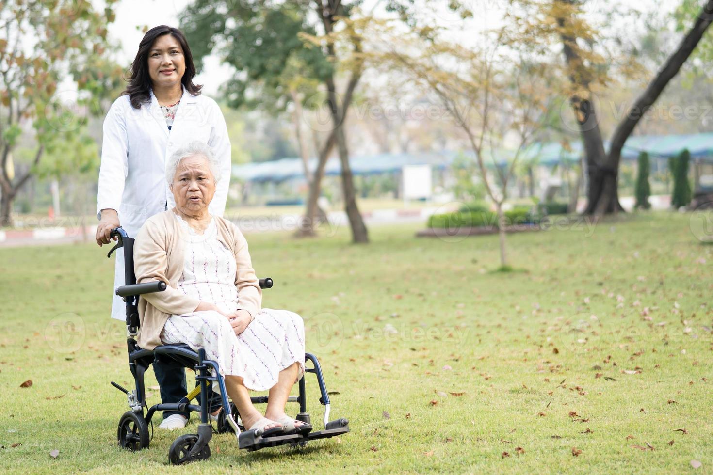 Médico ayuda y cuidado paciente asiático mayor o anciana mujer sentada en silla de ruedas en la sala del hospital de enfermería, concepto médico fuerte y saludable foto