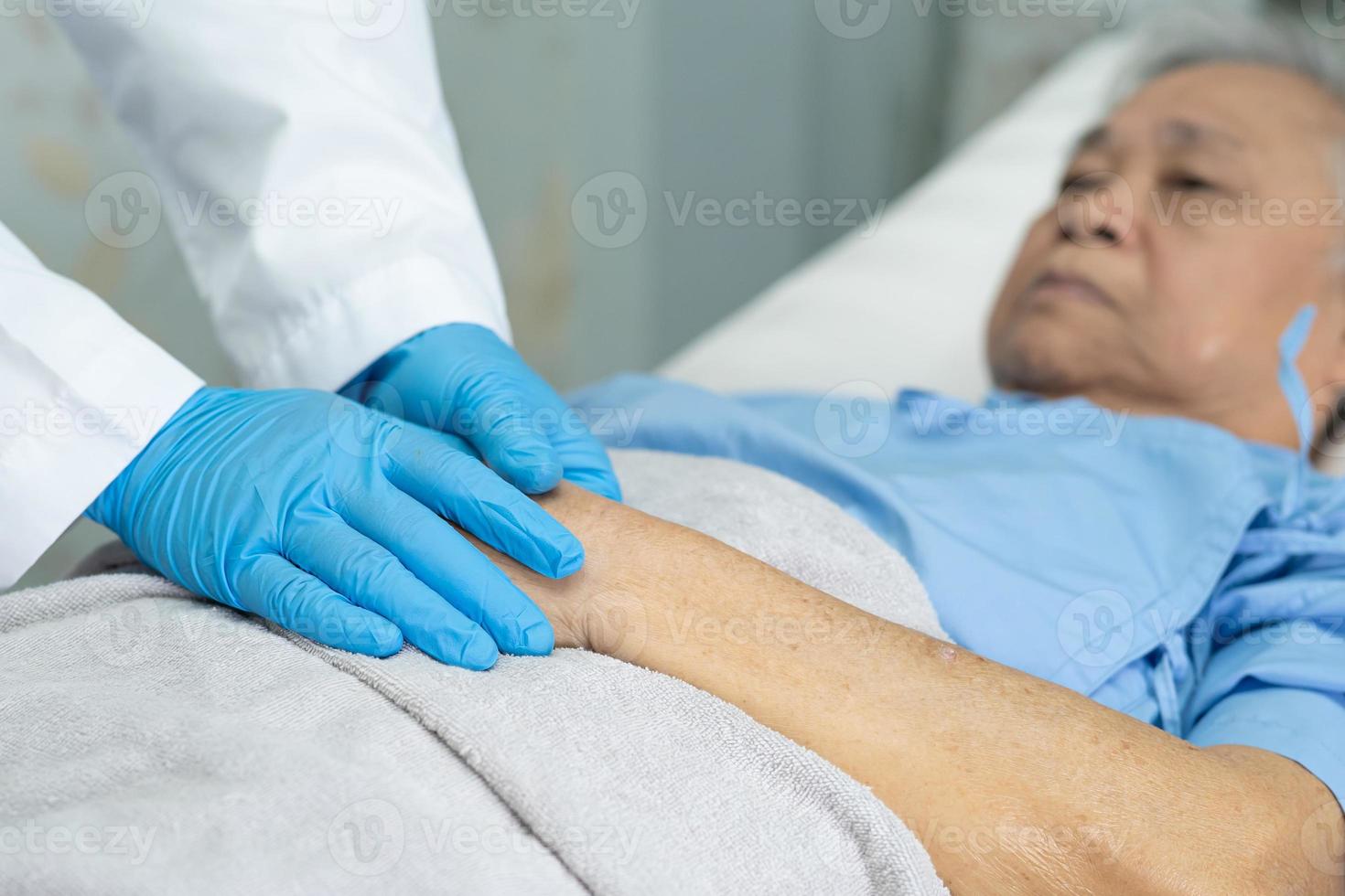 médico tomados de la mano anciana asiática mayor o anciana mujer infectada paciente con amor, cuidado, ayuda, aliento y empatía en la sala de cuarentena brote de coronavirus covid-19 en la sala del hospital de enfermería. foto